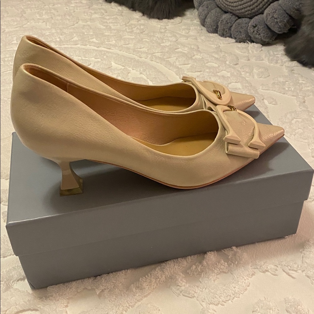 C. Paravano Cream Heels with C-shaped buckle accents.